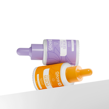 Glowx Two skincare serum bottles, one purple and one orange, on a white surface.
